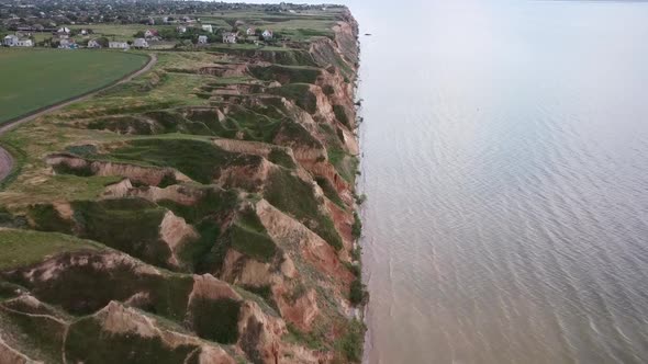 Quadcopter Flies Over Hills and a Wide River Approaching a Village