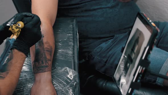 Male Tattoo Artist Tattooing a Client alt