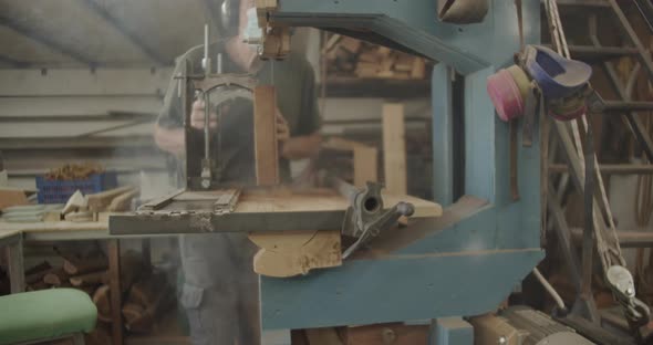 Carpenter cutting a wooden block with a saw machine