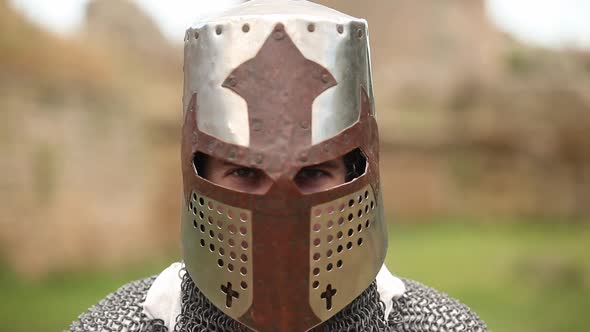 armed knight with in helmet looking in camera