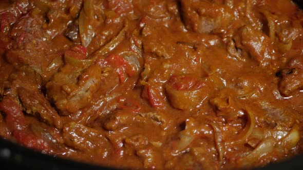 Indian beef curry being slow cooked. CLOSE UP. alt