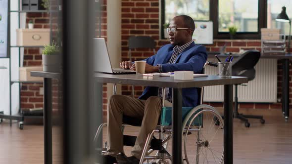 Project Manager Creating Report on Laptop in Disability Friendly Office alt