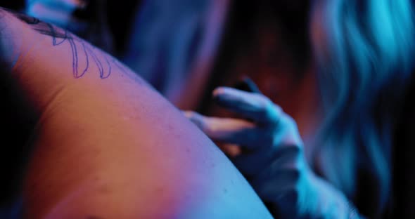 Tattooist explaining a client about a tattoo process in a studio. BMPCC 4K alt