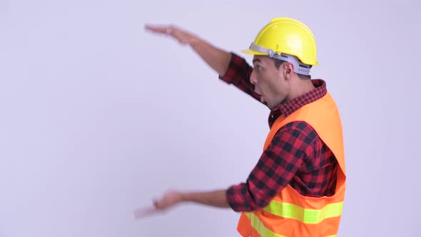 Young Happy Hispanic Man Construction Worker Snapping Fingers and Showing Something