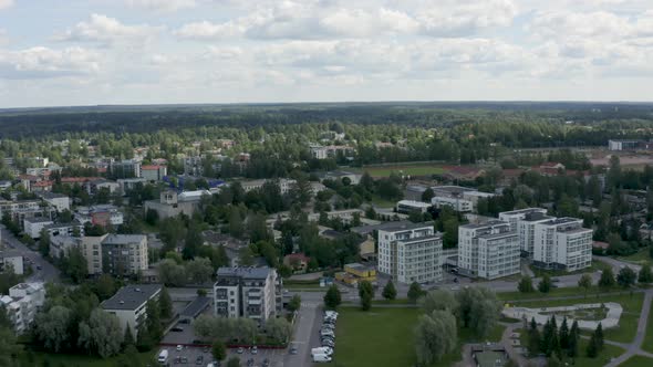 Fast aerial rising shot over buildings near Helsinki, Finland with a large sports field in the backg alt