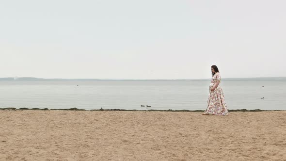 Pregnant Woman walking near the blue sea