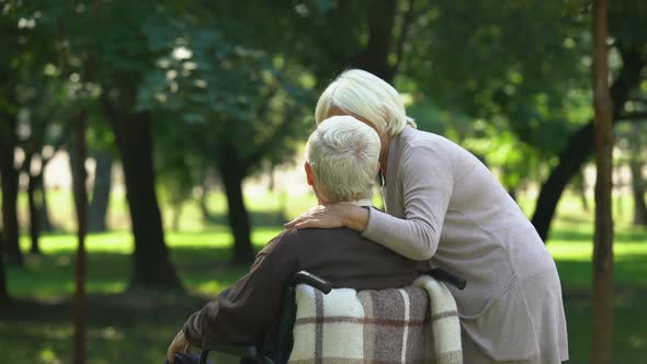 Lady Talking to Disabled Husband, Walking in Park, Woman Pointing at Distance alt