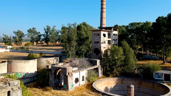 Aerial elevation view of a ruined cement factory with the silos and other processing parts of the co alt