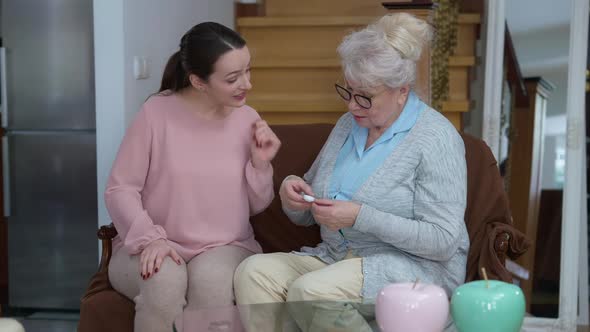 Positive Happy Young Woman Giving Contact Lenses Gift for Senior Lady in Eyeglasses alt