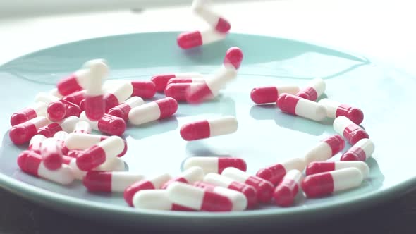 Red White Pills Fall on a Blue Plate Close Upslow Mo alt