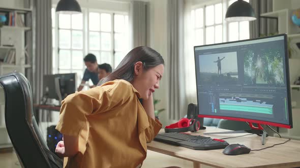 Female Video Editor Paining Her Back While Works With Footage And Sound On Her Personal Computer alt