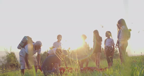 Teenagers Setting Up Tent at Campside on Hill in Summer alt
