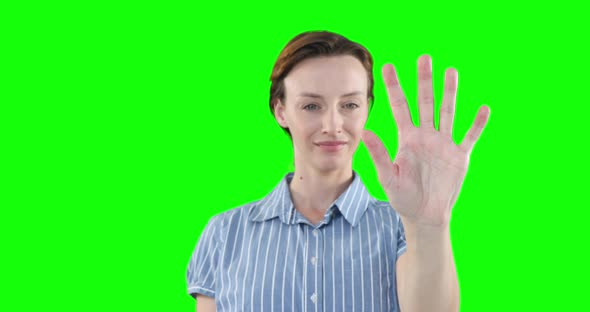 Caucasian woman raising hand on green background