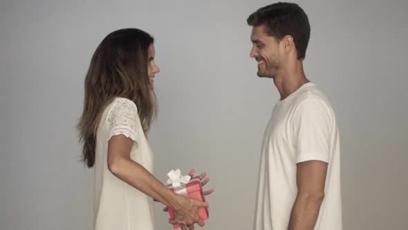 Woman surprising man with gift alt