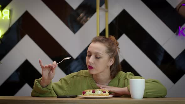 Attractive Casually Dressed Girl Enjoys Taste of Delicious Cake in Cafe