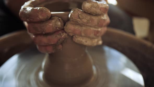 a Potter on a Potter's Wheel Makes a Tall Narrow Vase Out of a Wide Bowl alt