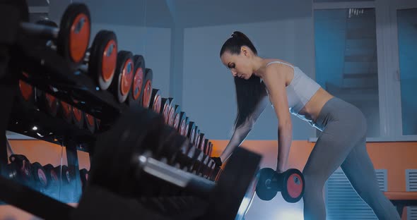Beautiful Girl Doing an Exercise on the Back of a Delta with Dumbbells alt