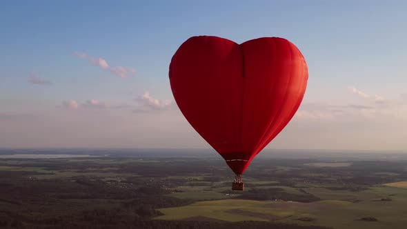 Red Heartshaped Balloon with People Over Green Fields and Forests