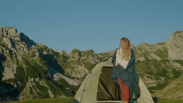 Happy travel woman with dreadlocks near the tent standing on top of hill looking at sunrise. alt