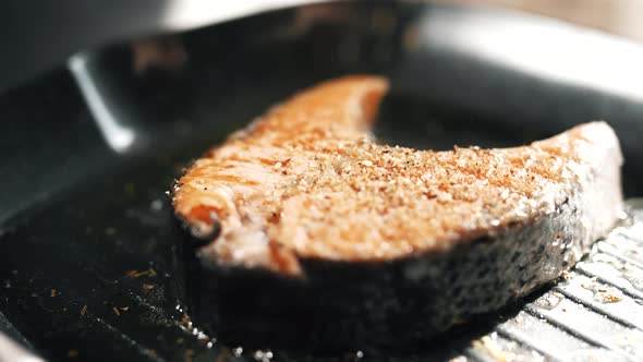 A Salmon Fillets on a Grill Plate is Sprinkling Spices alt