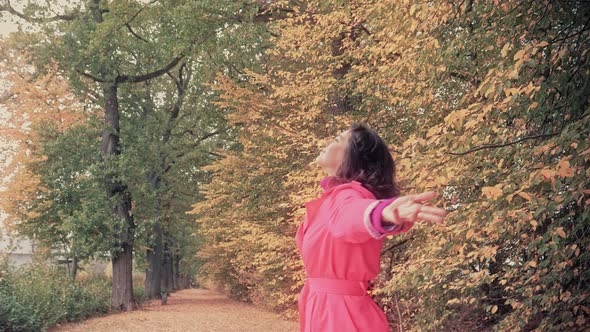 Happy Woman in a Red Cloak Walking in Autumn Park Concept of Freedom alt