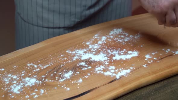 Men's Hands are Sprinkle with Flour to a Wooden Cutting Board alt