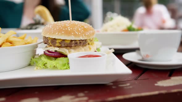A fast food dinner consisting of a hamburger, french fries and a cup of sauce served on a tray. alt