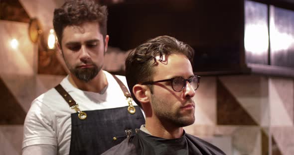 Male barber tying client apron alt