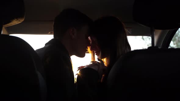 Portrait of Young Pretty Lovers Looking at Each Other with Tenderness and Sitting in Car alt
