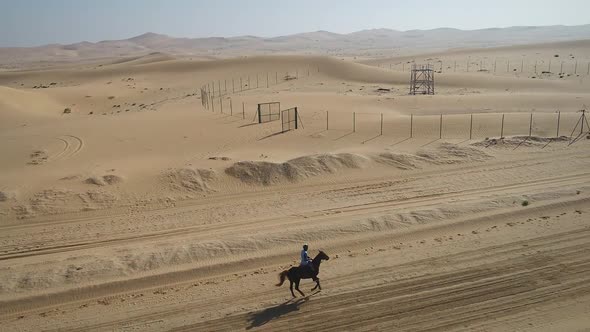 Aerial view of one person riding horse in the desert of Al Khatim in Abu Dhabi. alt
