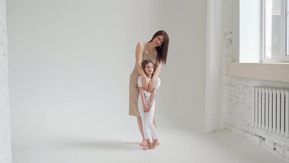 Mom and Daughter Pose in a White Photo Studio for a Photo Shoot alt