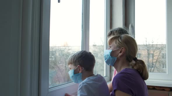 Family: father, mother, son and daughter in medical masks near the window 