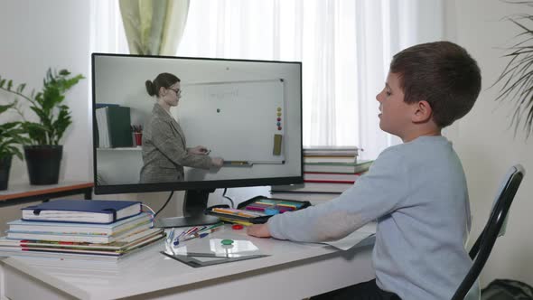 Online Education, Male Student at Home School Watching a Video Broadcast Using Modern Technologies