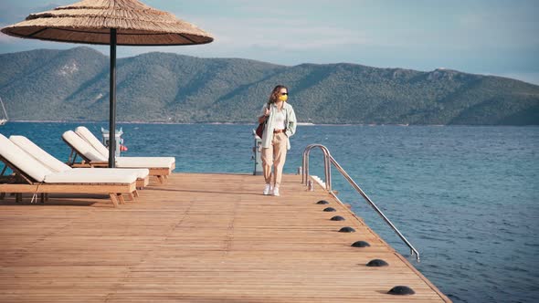 Woman Traveler in a Mask on His Face Walks on a Wooden Sea Pier, Summer Travel alt