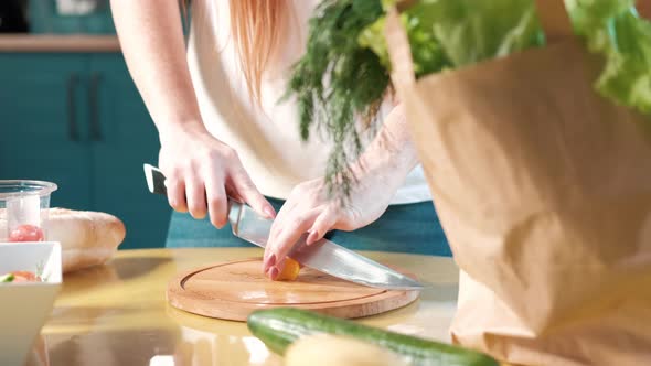 woman in the kitchen on the table cuts ripe tomatoes for a vegetable salad alt