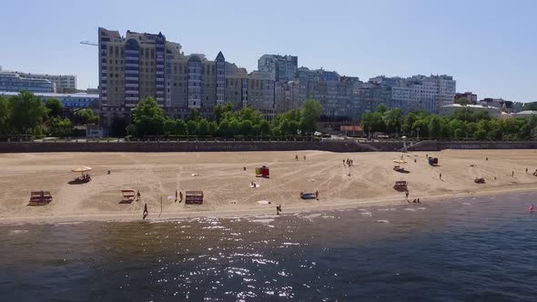 Sandy Beach on Shore of River in Modern City Aerial View in Summer Day