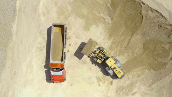 Bulldozer loading a truck with sand at sand extraction area,  alt
