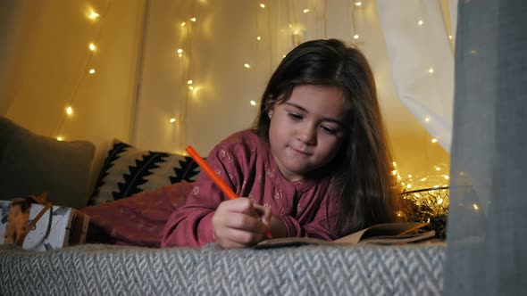 Little Girl Writes a Letter to Santa Claus with Wishes Lying on the Windowsill Decorated with a alt