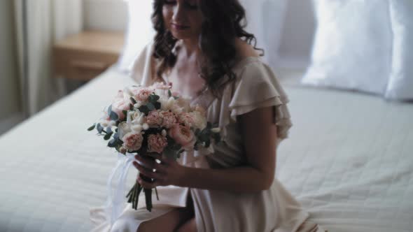 A Girl Sits on a Bed with a Large Bouquet of Flowers alt