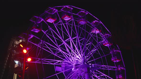 Illuminated Ferris Wheel Rotating in an Amusement Park At Night alt