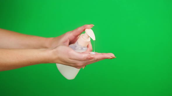 Washing Female Hands on Green Background Pushing Dispenser and Using Liquid Soap or Foam alt