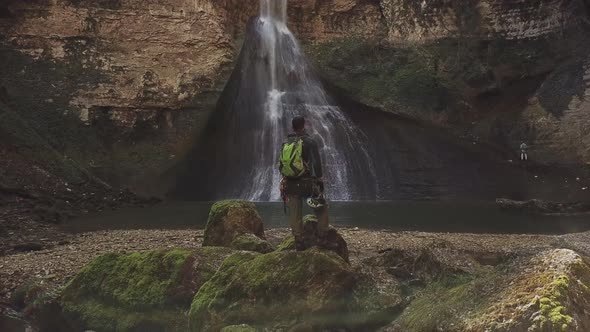 Speleologist Standing in Front of Waterfall at the Cave