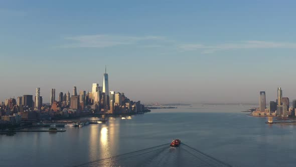 An aerial view of lower Manhattan and New Jersey from over the Hudson River at sunrise. The sun refl alt