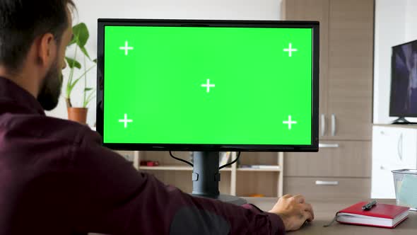 Side View of Man Sitting in Front of Computer with Big Green Screen Mock-up Chroma Typing on the alt