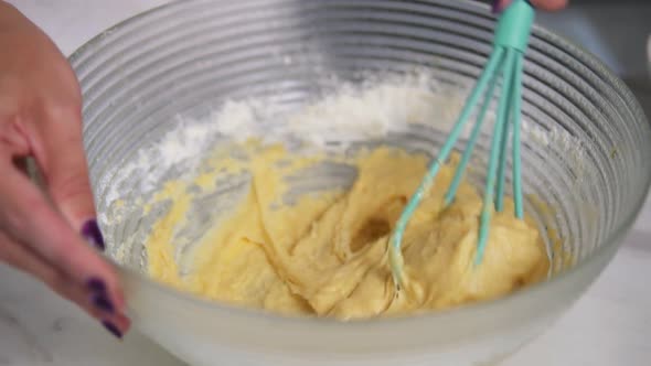 Woman Preparing Dough Mixing Ingredients Using Whisk in the Kitchen alt