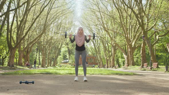 Sporty Woman in Activewear and Hijab Holding Heavy Barbell Over Head While alt