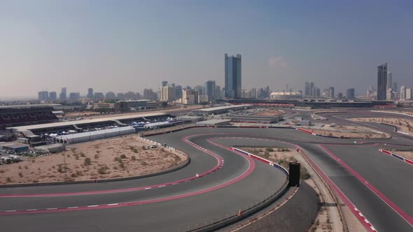 Aerial view of empty Dubai Autodrome race track, wavy corners, Dubai skyline