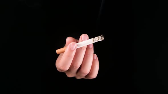 hand with smoking cigarette emerges from darkness, inviting the viewer to smoke alt