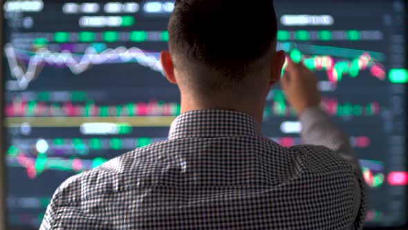 Back View of Millennial Stock Trader Working on Multiple Screens Analyzing Graphs alt