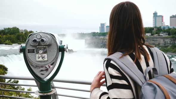 Happy Tourist Woman with Backpack Walks Up To Coin Operated Telescope at Niagara Waterfall alt